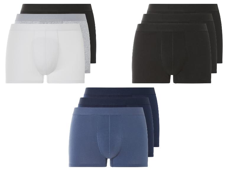 Drie pakjes met onderbroeken in zwart, grijs en blauw.