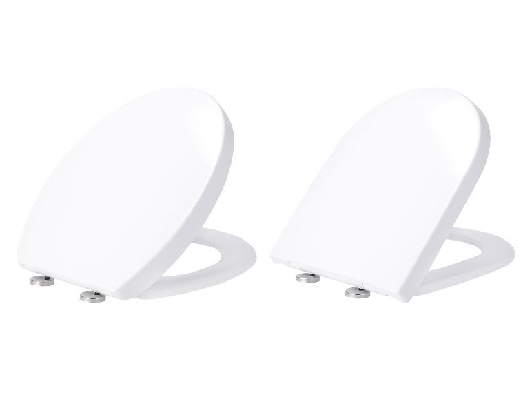 Deux abattants de toilettes blancs et ovales sur fond blanc