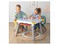 Deux enfants dessinent à une table blanche avec rangements et marqueurs.
