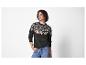 Vrouw in donkergroene trui met roze en wit patroon en jeans.