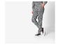 Persoon in grijs sweatshirt met luipaardprint en bijpassende joggingbroek met zwarte sneakers.
