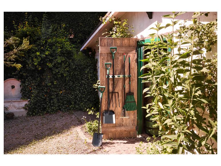 Outils de jardin suspendus à un mur en bois à l'extérieur d'un abri de jardin.