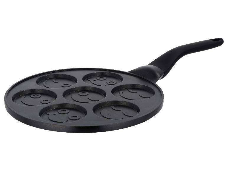 Zwarte pannenkoekenpan met zeven lachende gezichtsvormen.