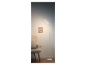 Moderne witte LED staande lamp naast een fauteuil.