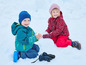 Twee kinderen in winterkleding spelen in de sneeuw.