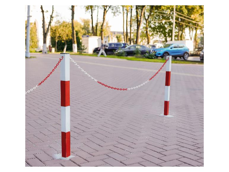 Rood-witte afzetpalen met ketting op een straat met geparkeerde auto's.
