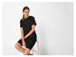 Femme en robe t-shirt noire, assise sur une chaise.