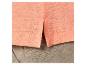 T-shirt corail et pantalon beige en lin.