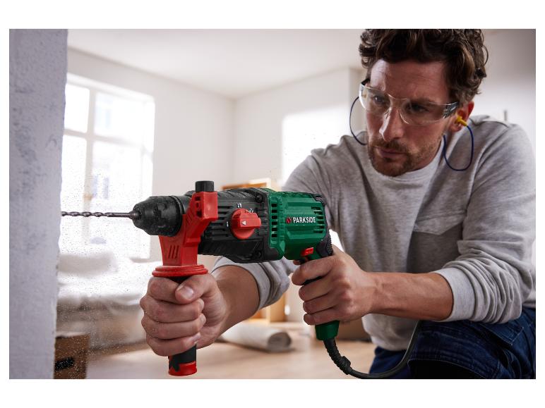 Een man boort een gat in een muur met een Parkside boorhamer.