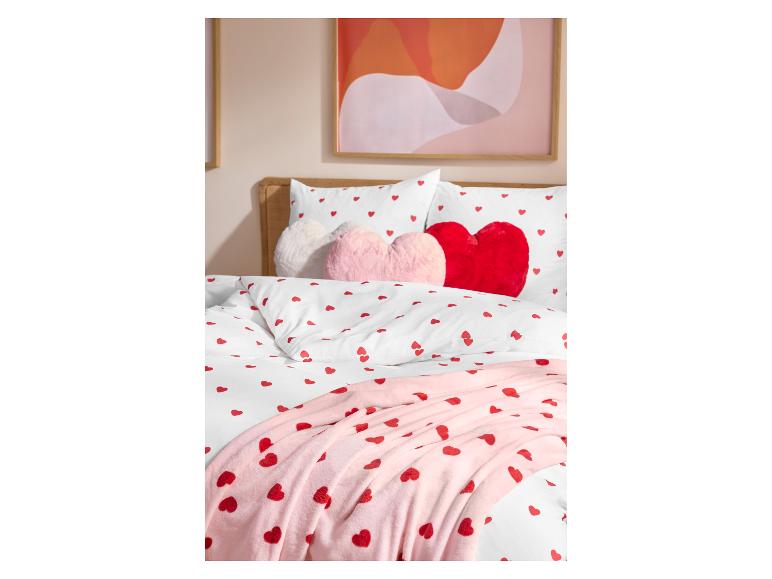 Lit avec parure de lit blanche à motifs de cœurs et coussins roses en forme de cœur