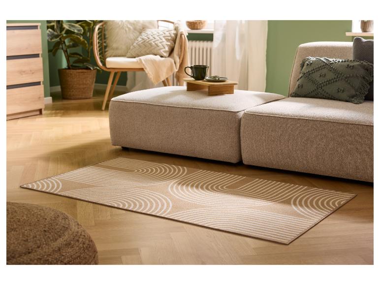 Woonkamer met beige bank, patroonkleed en houten meubels.