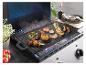 Plaque de grill avec diverses viandes et fruits de mer, y compris poulet, crevettes et saucisses.
