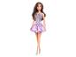 Barbiepop met bruin haar, draagt een glinsterende paarse jurk en zilveren sandalen.