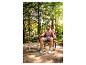 Een man zit op een rode campingstoel aan een telescopische tafel in het bos.