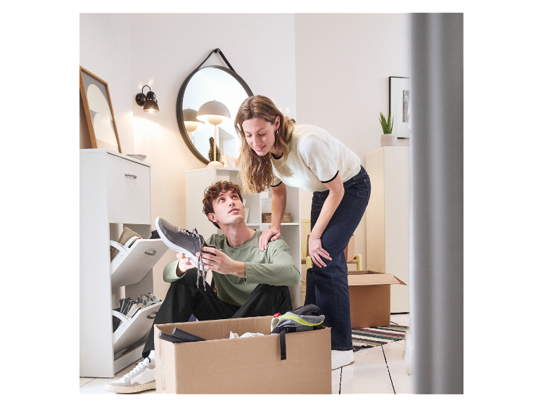 Jeune couple déballant des cartons de déménagement, essayant des chaussures.