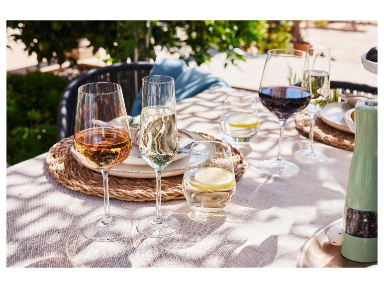 Des verres à vin, de l'eau et du citron sur une table en plein air.