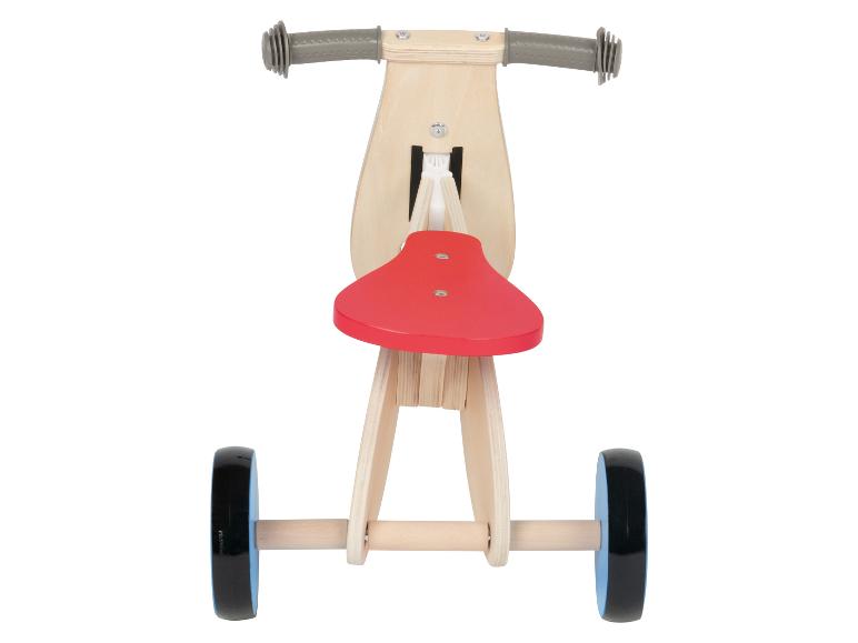 Draisienne en bois avec une selle rouge et des roues noires.
