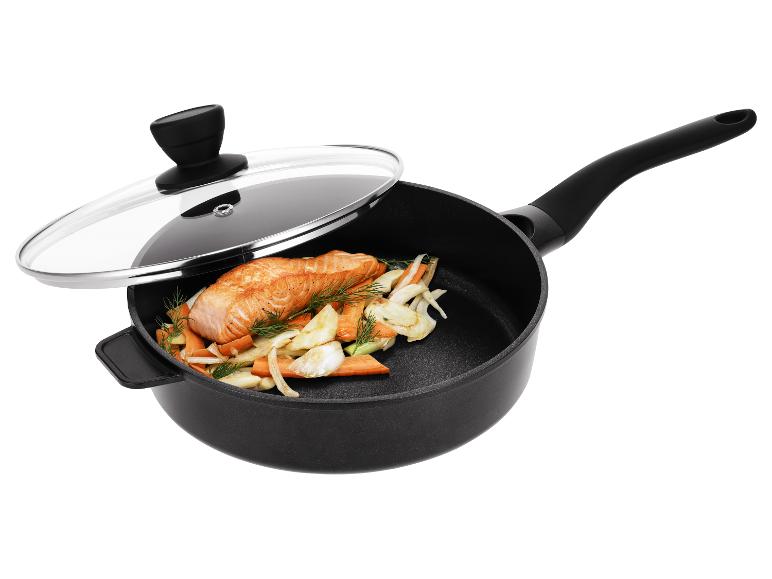 Poêle noire avec couvercle en verre, contenant du saumon et des légumes.