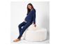 Femme enceinte en ensemble de vêtements de détente de maternité bleu marine, assise sur un banc blanc texturé.