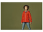 Een kind draagt een oranje softshell jack met een capuchon.