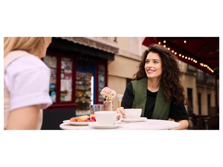 Twee vrouwen genieten van koffie en ontbijt buiten.