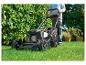 Man maait gras met een Parkside grasmaaier in een tuin.
