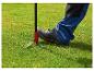Le pied d'une personne dans une chaussure de travail appuyant sur un désherbeur pour retirer une mauvaise herbe de l'herbe verte.