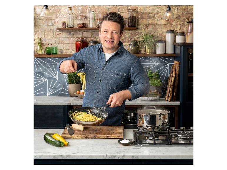 Jamie Oliver cuisine des pâtes dans une cuisine avec des murs en briques et des comptoirs en marbre.