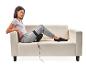 Une femme assise sur un canapé blanc avec un coussin de massage sur sa jambe.