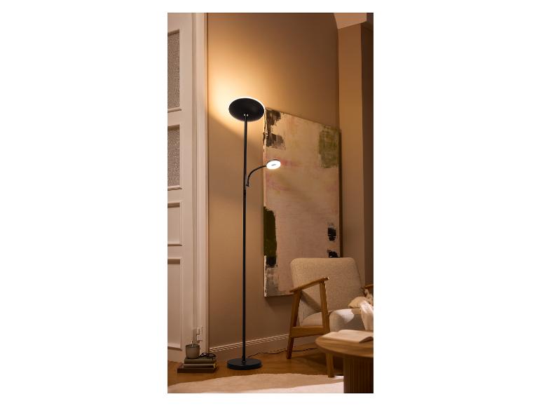 Lampadaire noir à deux lumières dans un coin de pièce avec un fauteuil et un tableau.