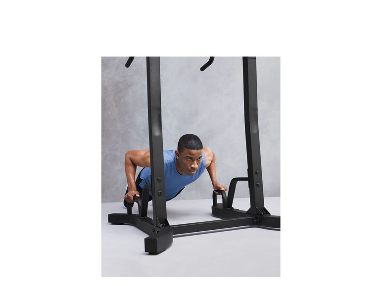 Un homme faisant des pompes sur un rack d'entraînement noir.