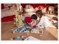 Deux enfants jouent sur le sol avec des jouets en bois et un puzzle.