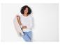 Lachende vrouw in een wit shirt met lange mouwen en jeans, met een beige jas.