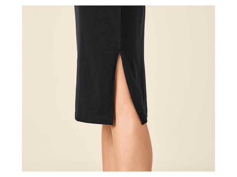 Détail d'une jupe noire avec une fente latérale, montrant la jambe d'une personne.