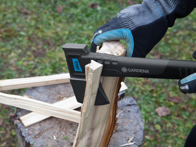 Een persoon gebruikt een Gardena bijl om hout te hakken.