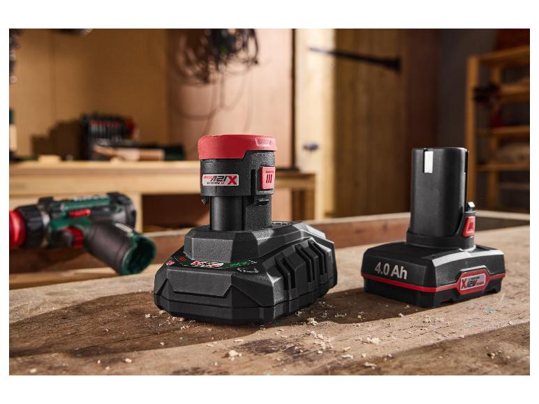 Deux batteries d'outils électriques sur un établi en bois, avec une perceuse en arrière-plan.