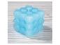 Bougie bleue en forme de cube avec motif géométrique sur une surface en bois