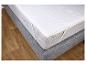 Un matelas blanc avec une tapisserie grise, sur un sol en bois.