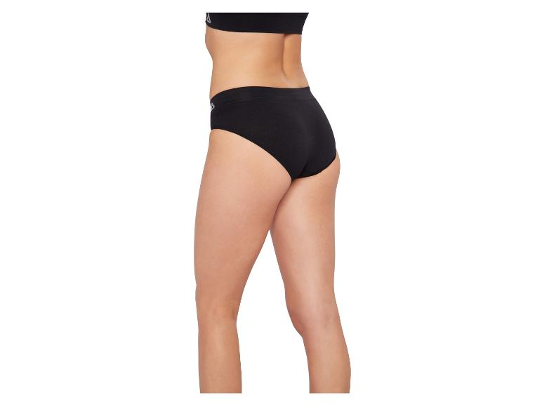 Femme portant une culotte noire et un soutien-gorge de sport noir, vue de côté.