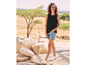 Een vrouw draagt een zwarte tanktop, denim shorts en espadrilles.