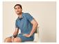 Man in blauwe poloshirt en korte broek zit op een stoel.