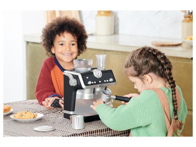 Deux enfants jouent avec une machine à café jouet Delonghi.
