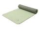 Tapis de yoga Crivit vert clair et gris, partiellement roulé, avec texture antidérapante.
