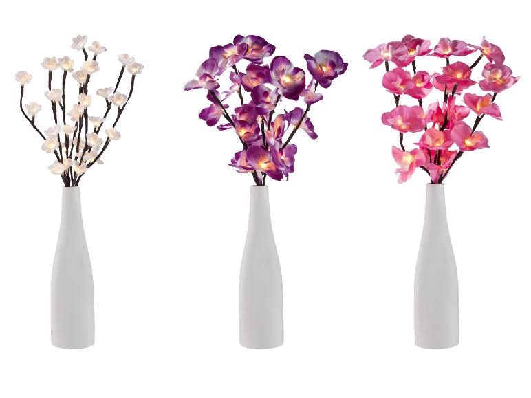 Drie witte vazen met verlichte bloemen: wit, paars en roze.