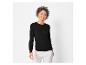 Een vrouw draagt een zwarte trui en witte broek.