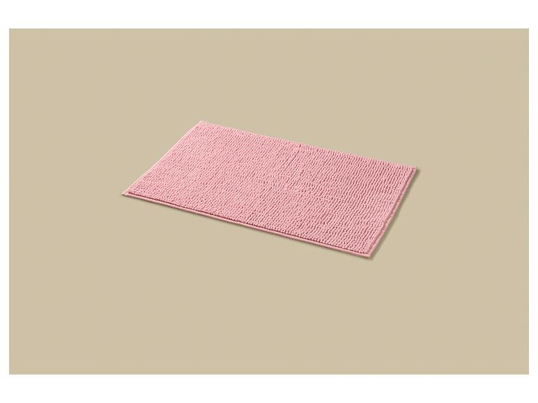 Roze rechthoekig badmatje op een beige achtergrond.