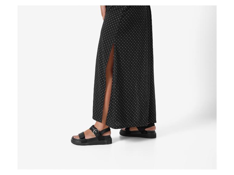Sandales plates et robe longue à pois noirs.