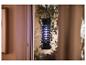 Zwarte insectenlamp met blauw licht hangend bij een raam met gordijnen