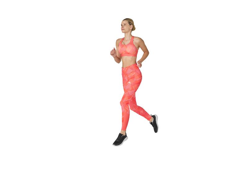 Vrouw in oranje sporttop en legging aan het hardlopen.