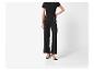 Femme en T-shirt noir et pantalon large à boutons dorés, talons noirs